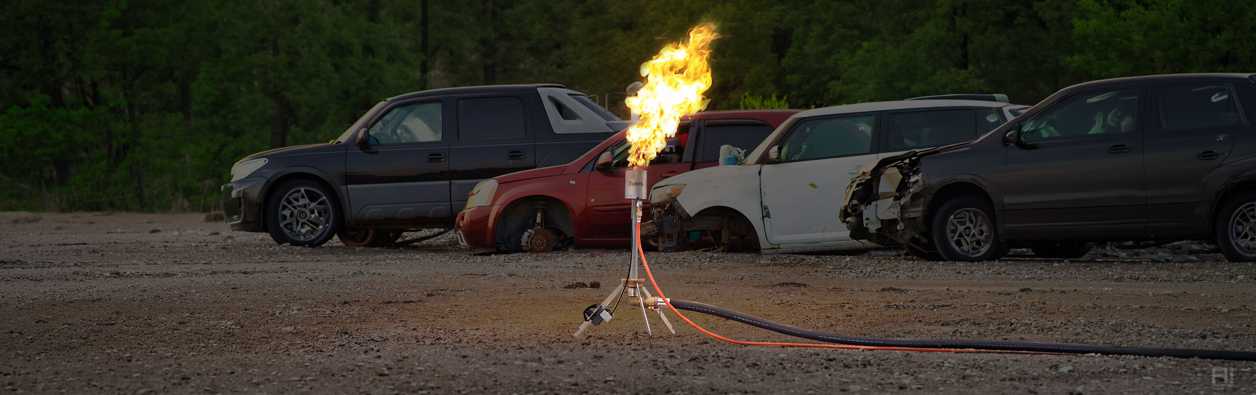 Header Autotanks abfackeln, Mobile Gasfackel M brennenden im Vordergrund, Hintergrund Autos und ein Schrottplatz